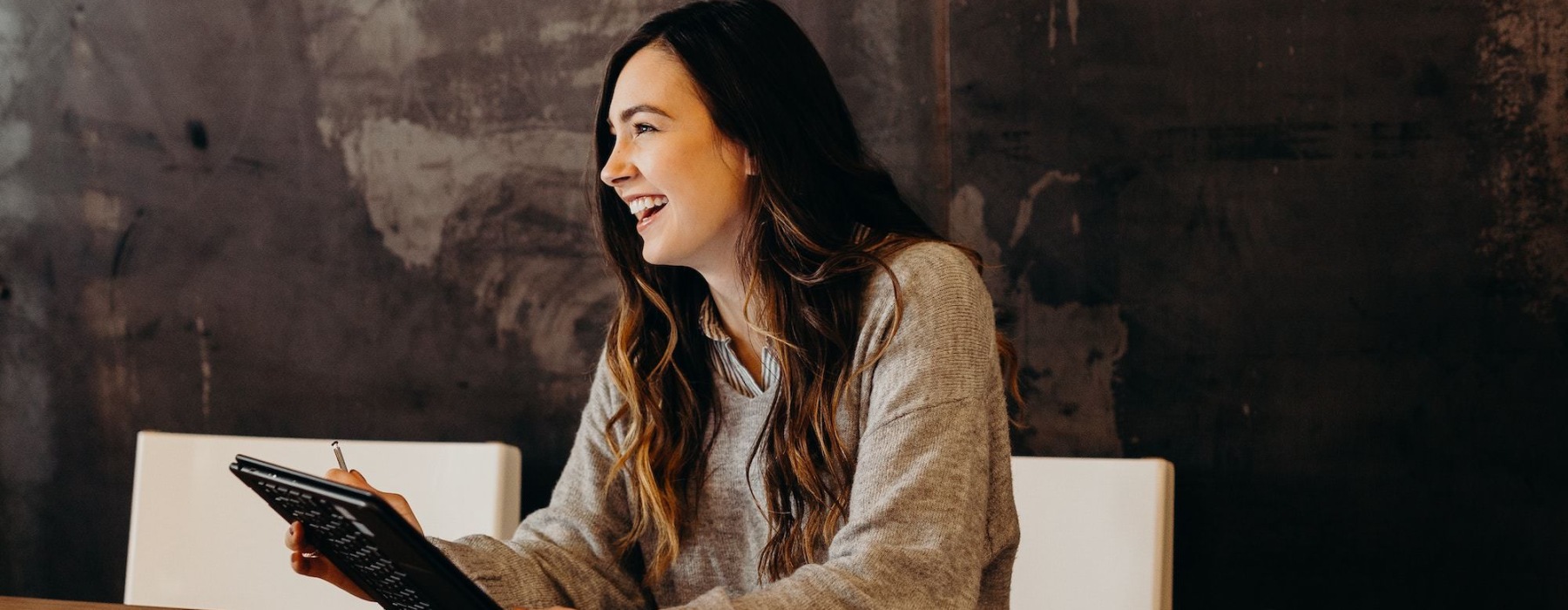 Woman with brown hair siting at a table with a laptop